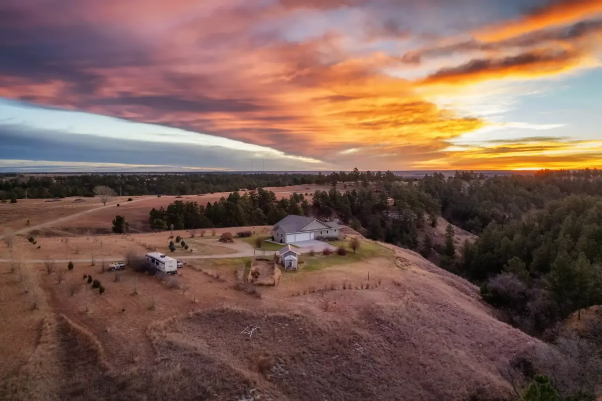 A large house on a hillside at sunrise.