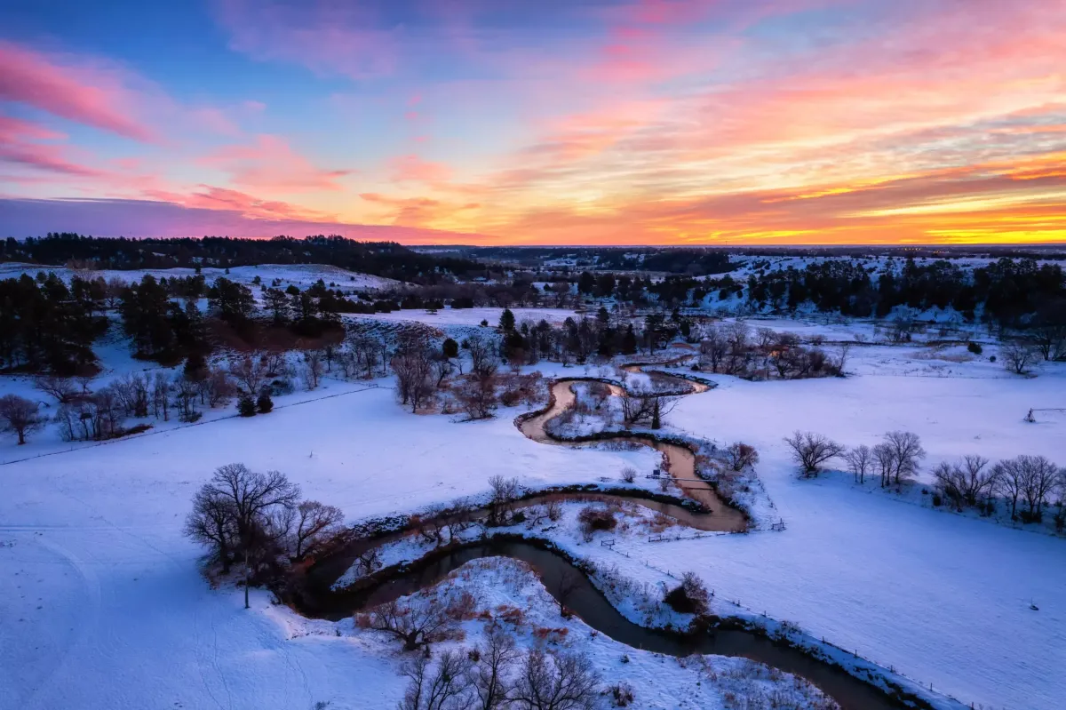 A photo of the Minnechaduza Creek a sunrise with snow and a beautiful colorful sky.