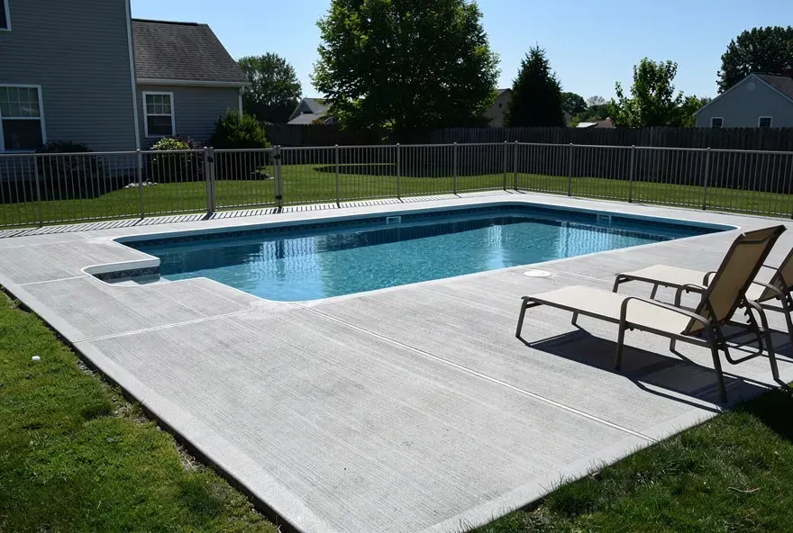 Freshly finished textured concrete pool deck surrounding a backyard pool in Bear, Delaware.