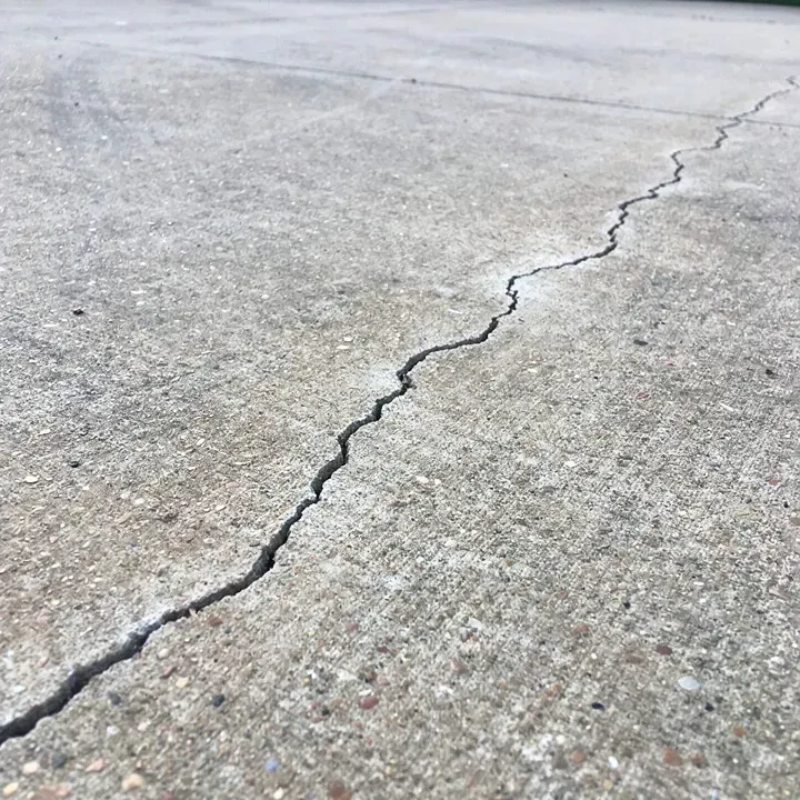 Close-up of a hairline crack in an aging concrete driveway in Bear, Delaware.
