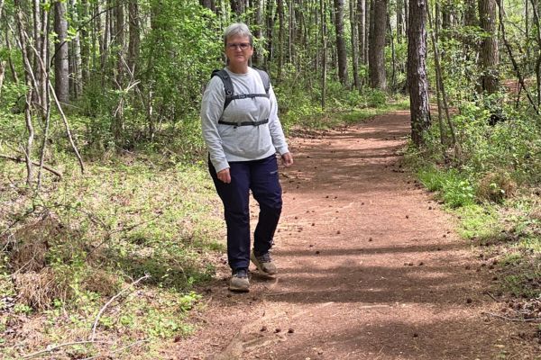 Woman walking on a wooded trail, reflecting on building a business with support instead of doing it alone