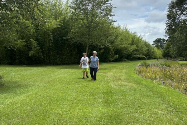 Woman and young boy walking together through a peaceful green landscape, symbolizing healing, connection, and moving forward after emotional release