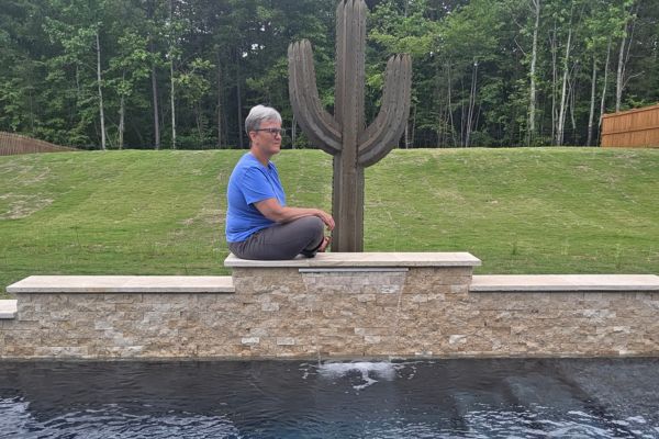 Claudette Eames sitting thoughtfully beside a water feature outdoors, reflecting on building a business that fits real life and personal growth