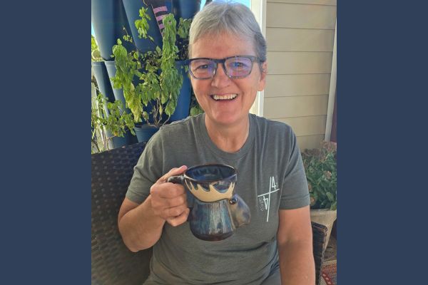 Claudette Eames enjoys a quiet morning coffee on her porch, reflecting the freedom of building a business that fits real life, creating space for family, purpose, and meaningful work without putting life on hold.
