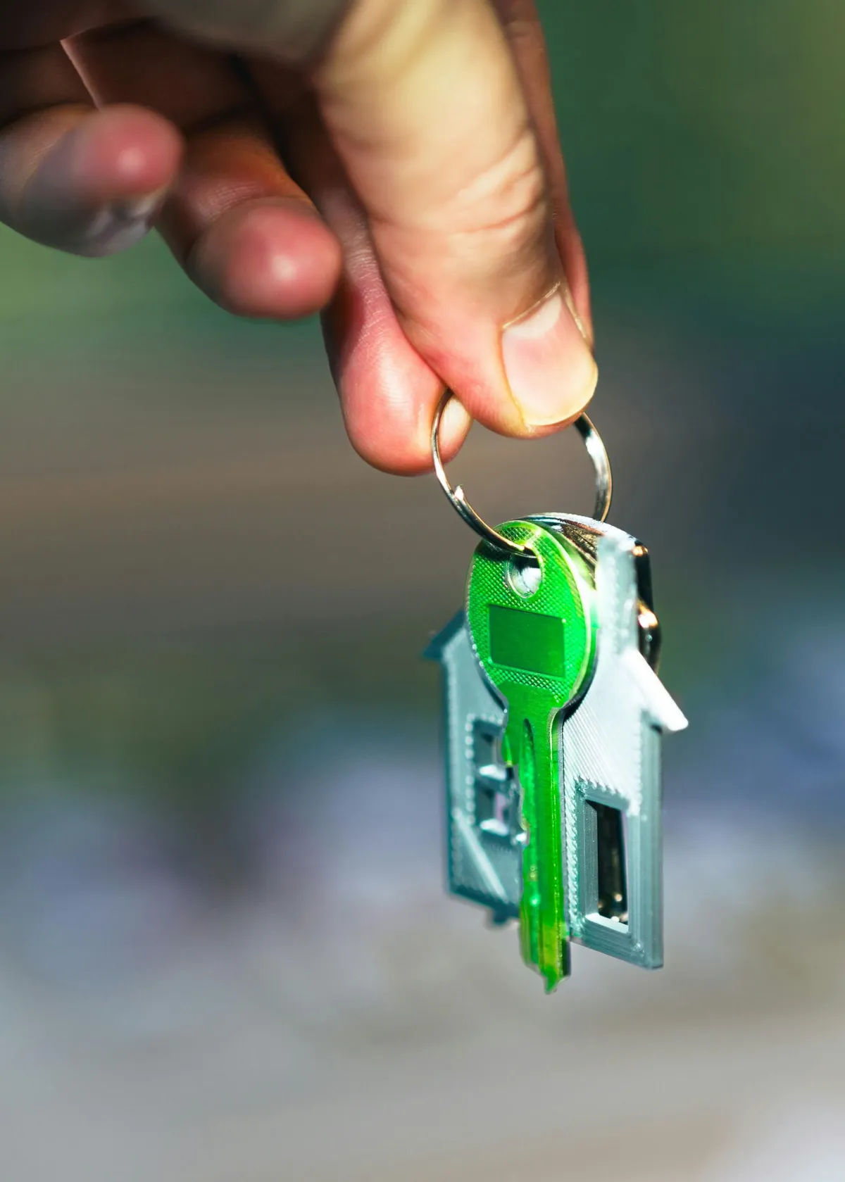 a hand holding a keychain with house on it