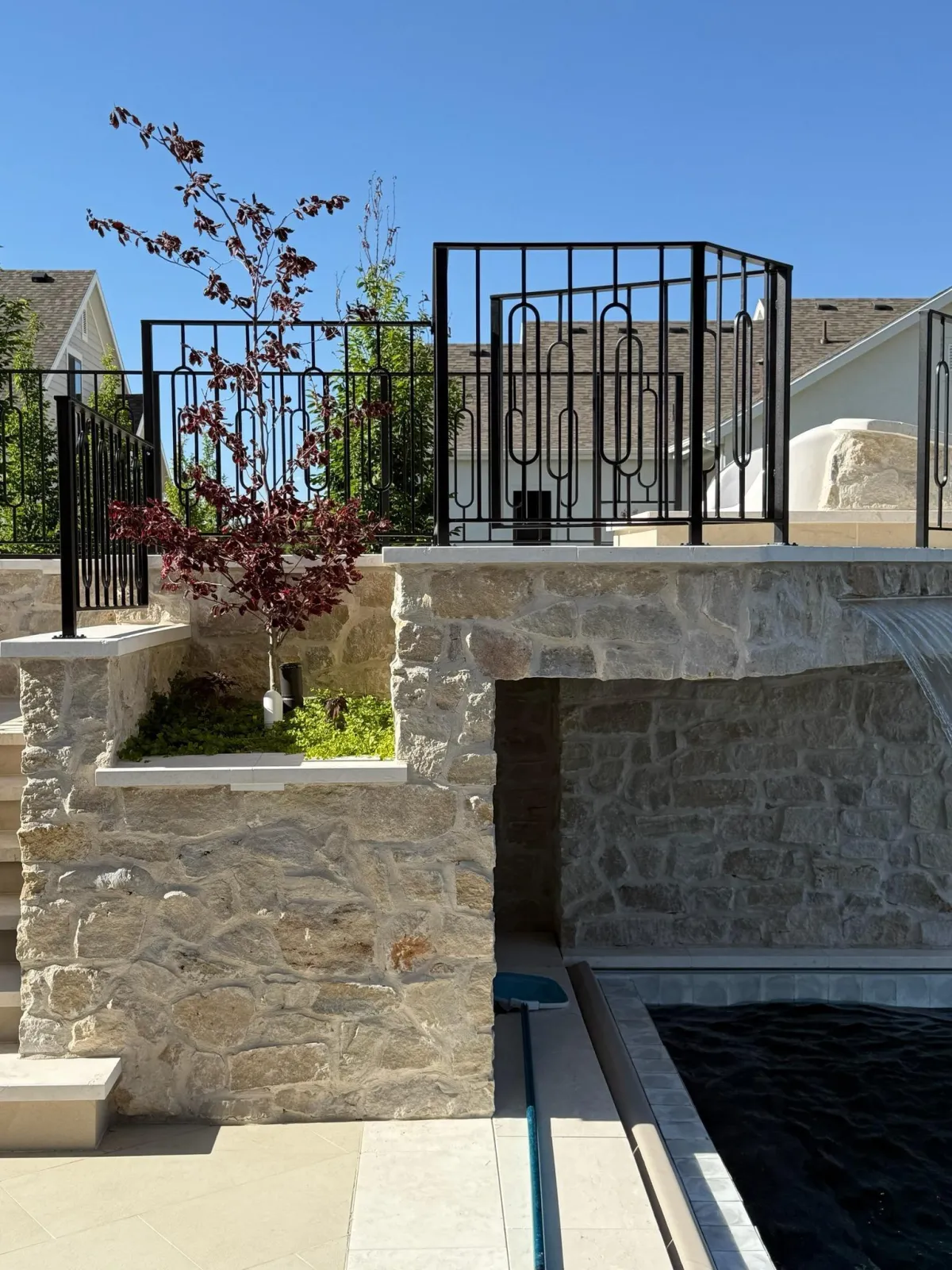 custom outdoor railing over a waterfall, looking over a pool