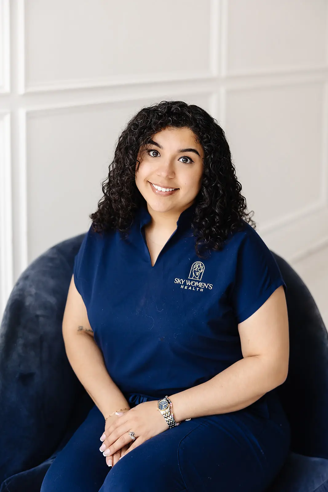 Gabriela Miranda, BS - Female healthcare professional in navy scrubs smiling confidently at Sky Women’s Health clinic.