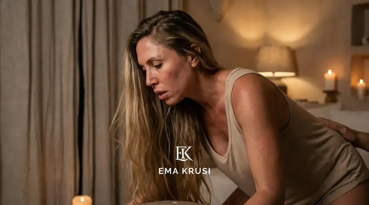 Gros plan d’une femme en travail, penchée vers l’avant et soutenue, dans une chambre éclairée à la bougie.