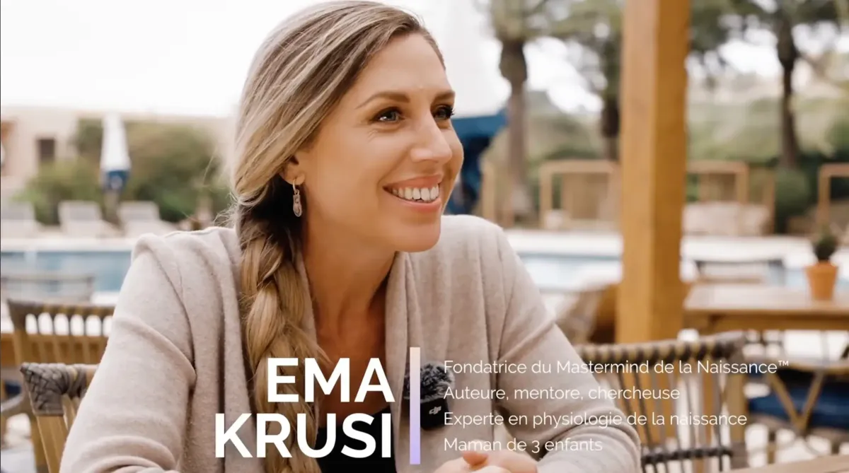 Ema Krusi en interview en extérieur près d’une piscine, souriante, présentant son travail sur la physiologie de la naissance.