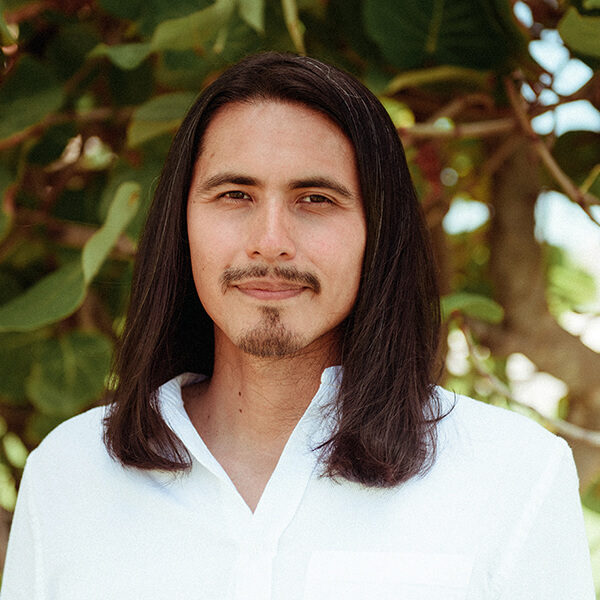 Headshot of Dr. Gustavo Kusi Monje, an Indigenous wellness educator based in Washington DC, smiling in front of a natural background.