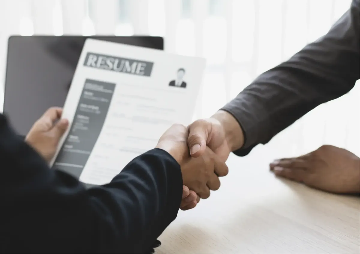 Job interview handshake over resume between recruiter and applicant.