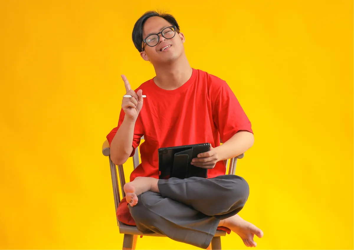 Young person with disability displaying confidence and independence while using digital technology on tablet, representing successful outcomes from vocational rehabilitation, life skills training, and transition services