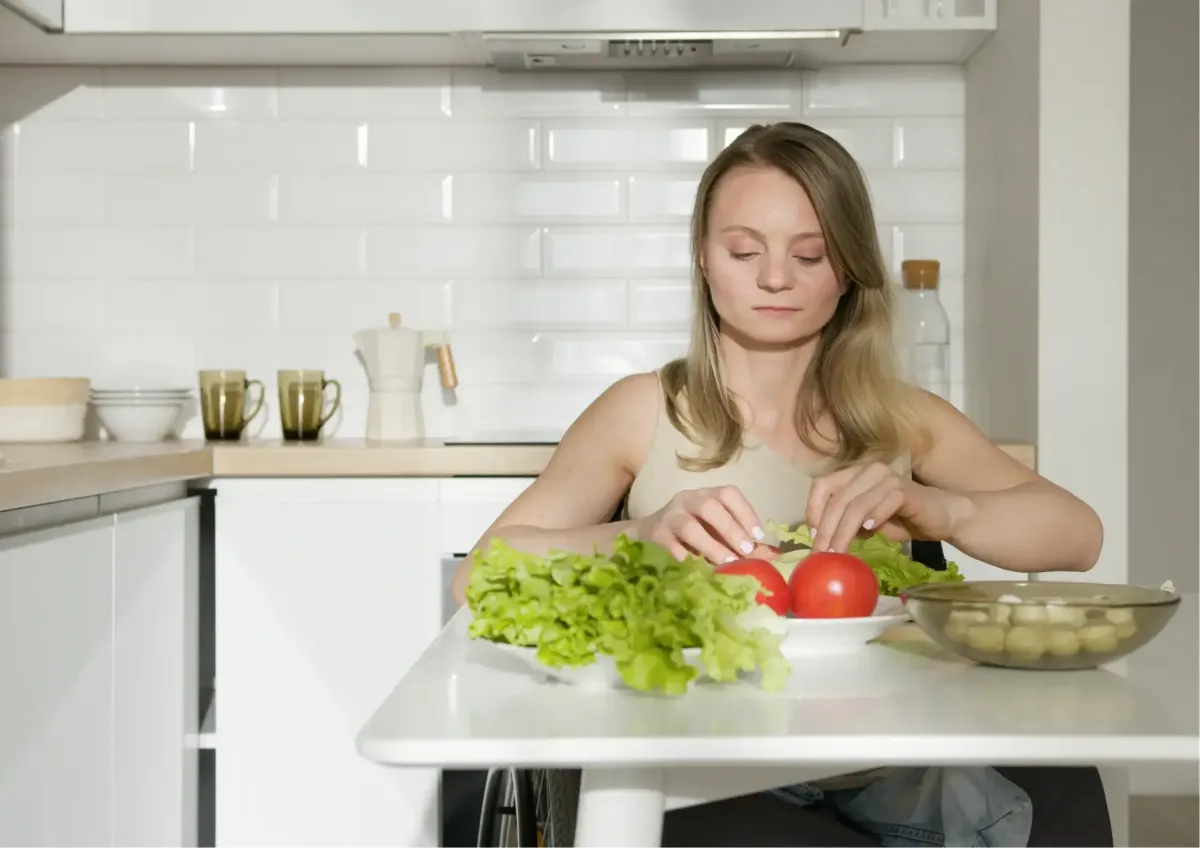 A young woman preparing fresh food in an accessible kitchen as part of an independent living skills meal prep task.