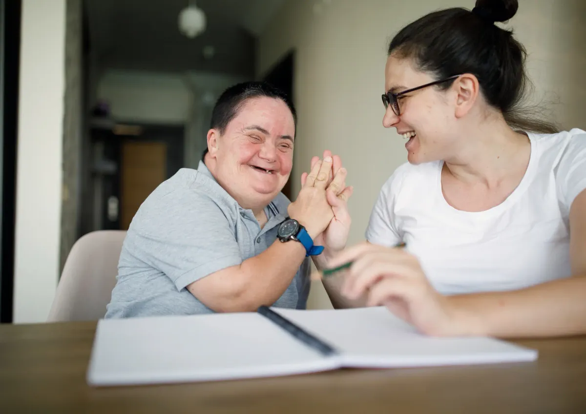 Job coach and job seeker celebrate with a high five while working on an employment plan