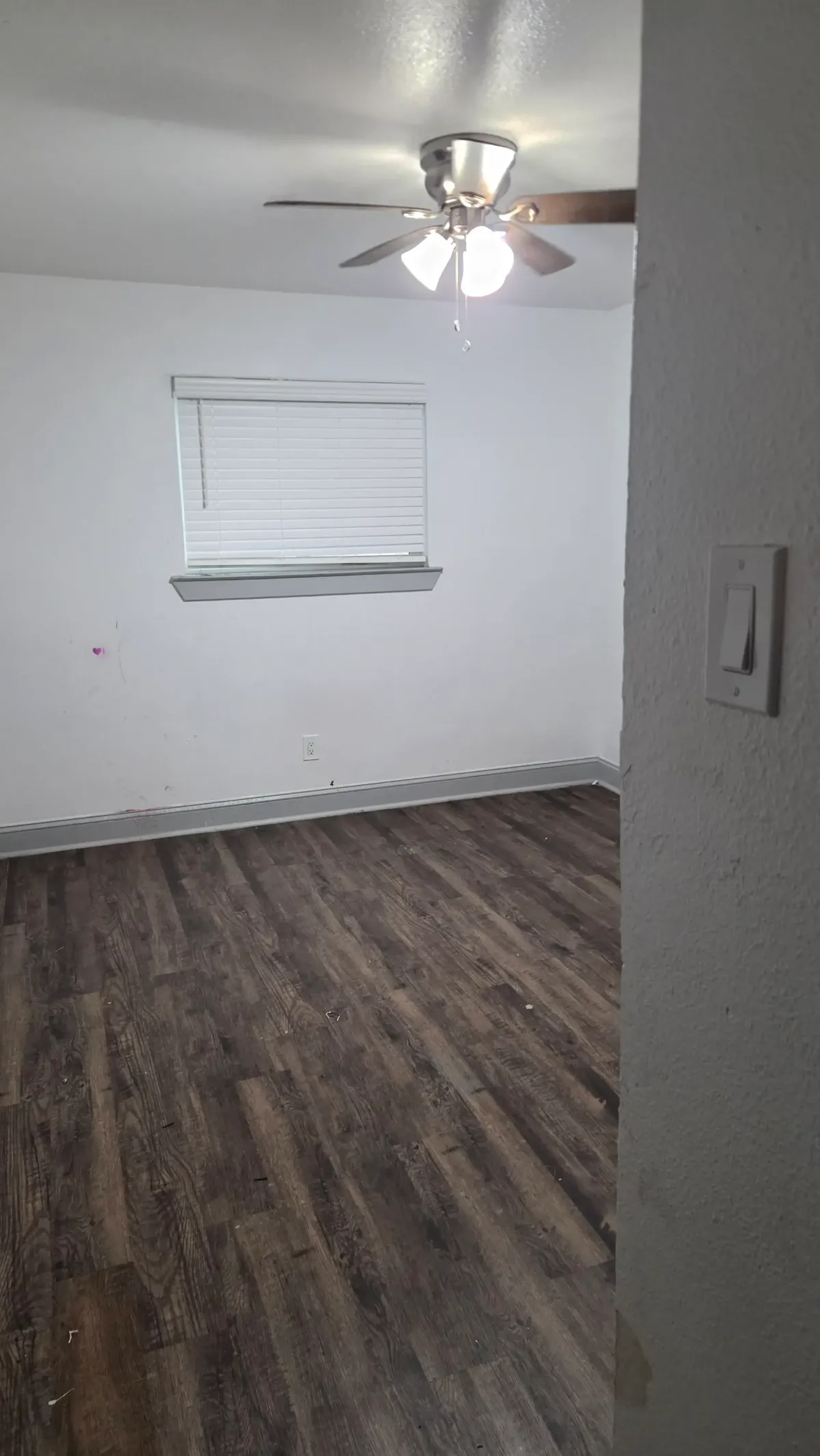 Family preparing for apartment cleanout, hanging wall art, with moving boxes and clutter in a bright living room setting.