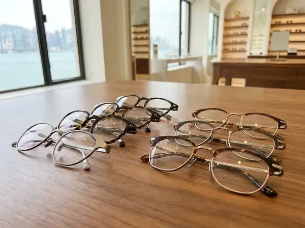 Collection of premium eyeglass frames showing titanium, acetate, and hybrid materials on wooden display at San Francisco optometry practice