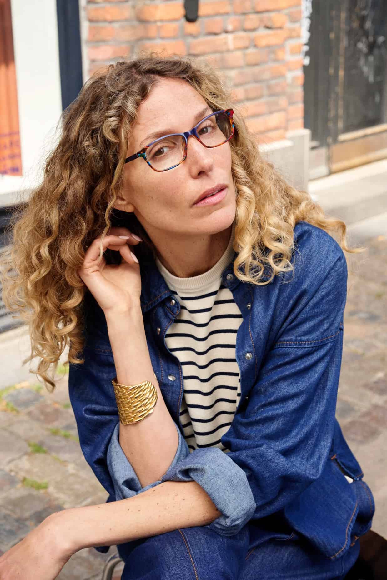 Woman wearing colorful ProDesign eyeglasses and a denim jacket on a city street.