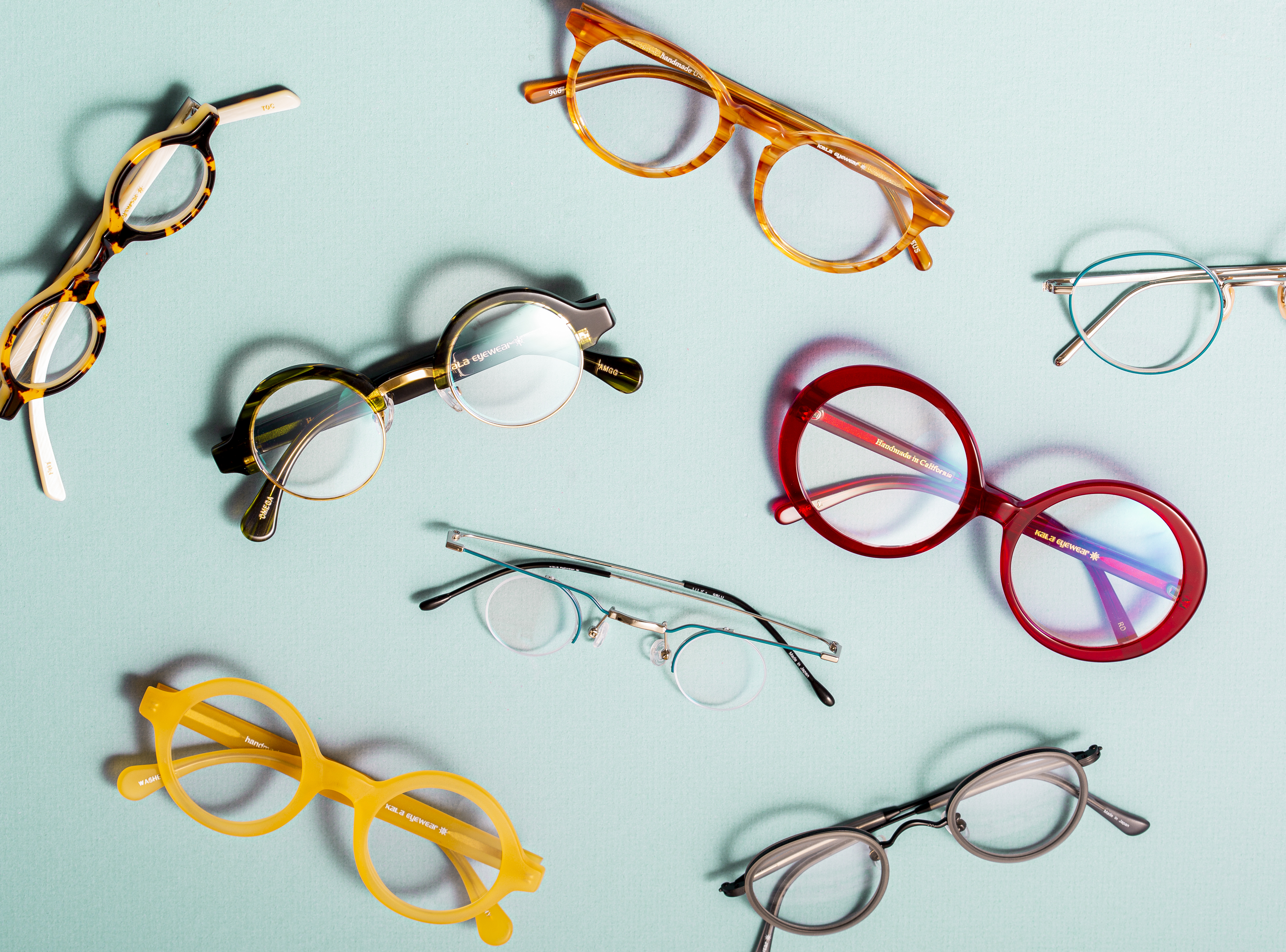 Colorful designer eyeglass frames arranged on a light blue background.