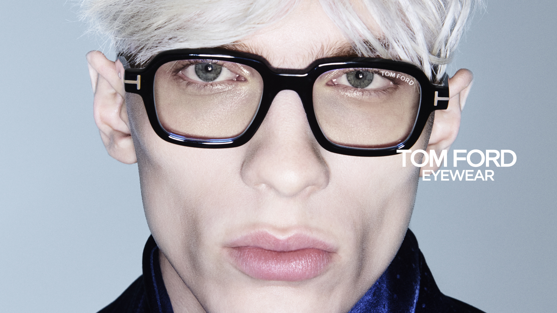 Close-up of a model wearing oversized black Tom Ford eyeglasses with signature gold T accents.
