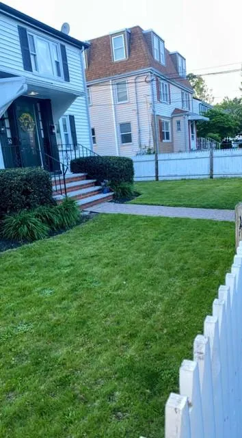 Well-maintained lawn behind a classic white picket fence in Boston MA