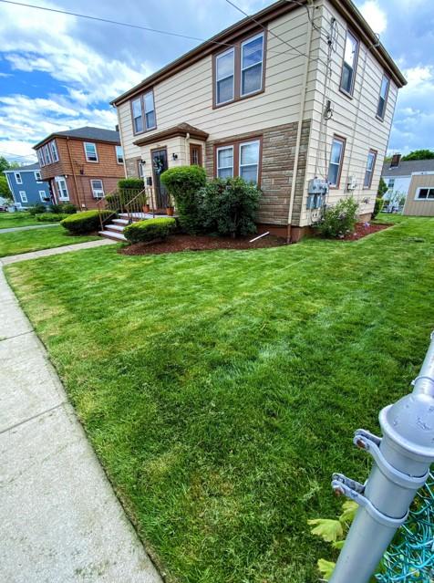 Yard with freshly mowed grass and neatly trimmed hedges around the front door