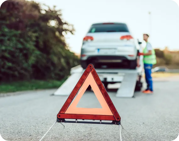 Warning triangle and tow truck symbolizing LH3 24/7 roadside assistance and towing service"