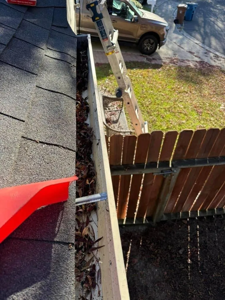 Professional gutter cleaning technician on ladder debris removal residential home Solano County Teodor Window Solar