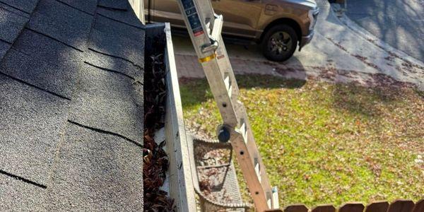 Professional gutter cleaning technician on ladder debris removal residential home Solano County Teodor Window Solar