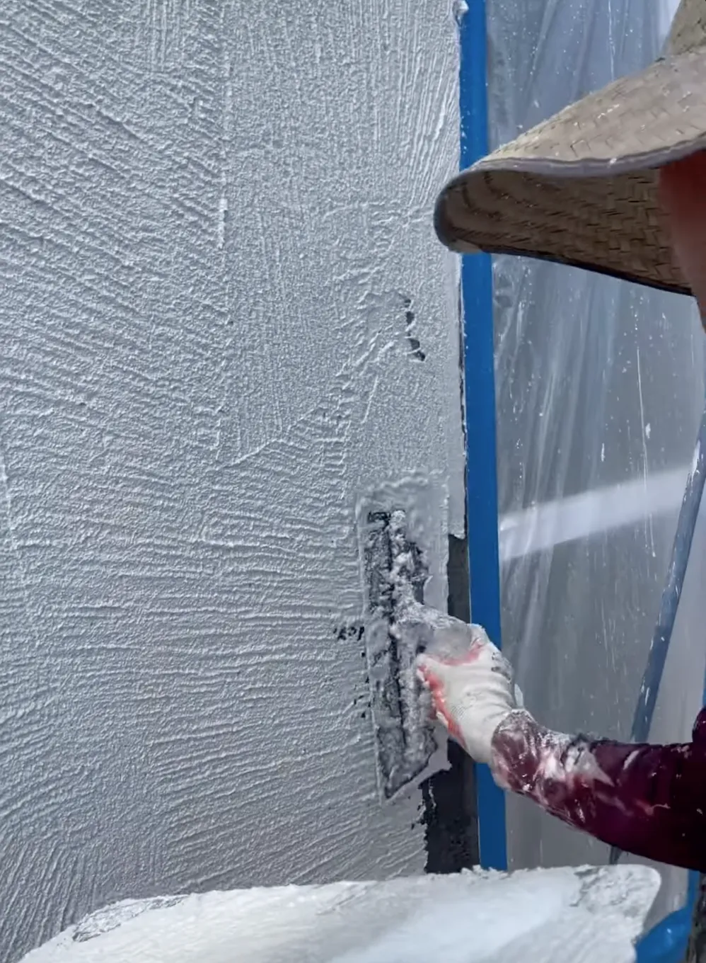 Man with hat applying new stucco to a wall