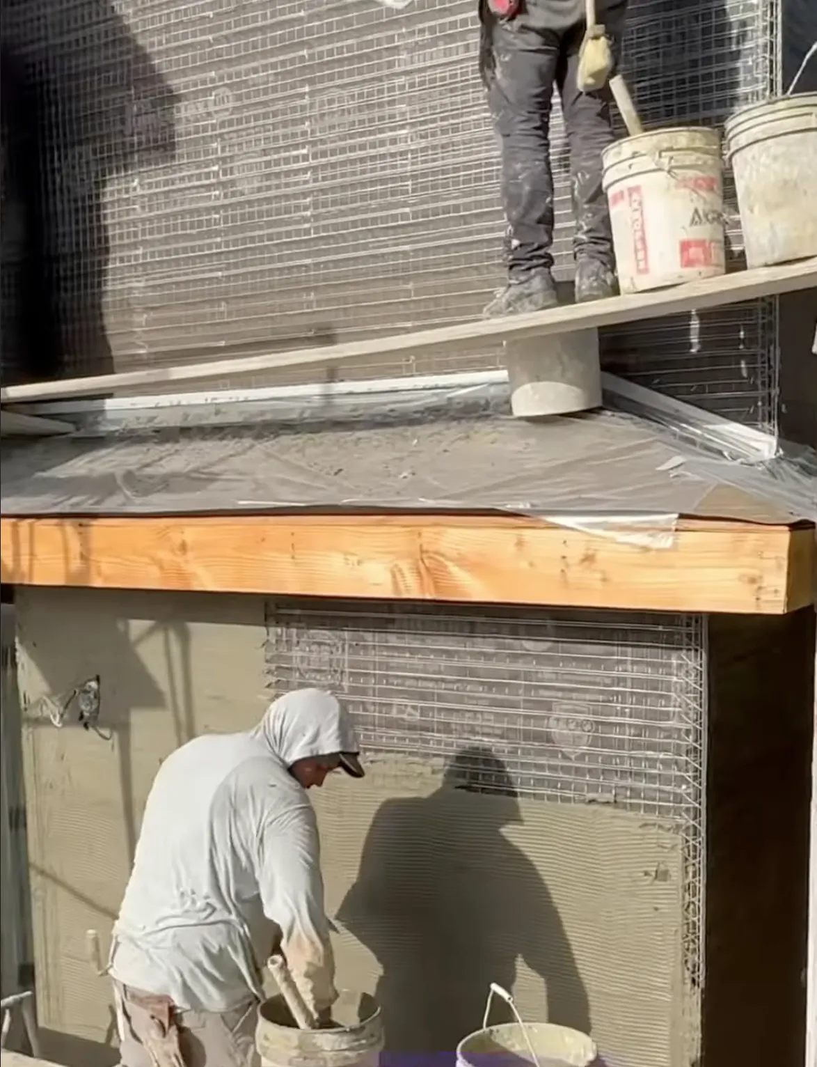 two men workion applying stucco to new construction 