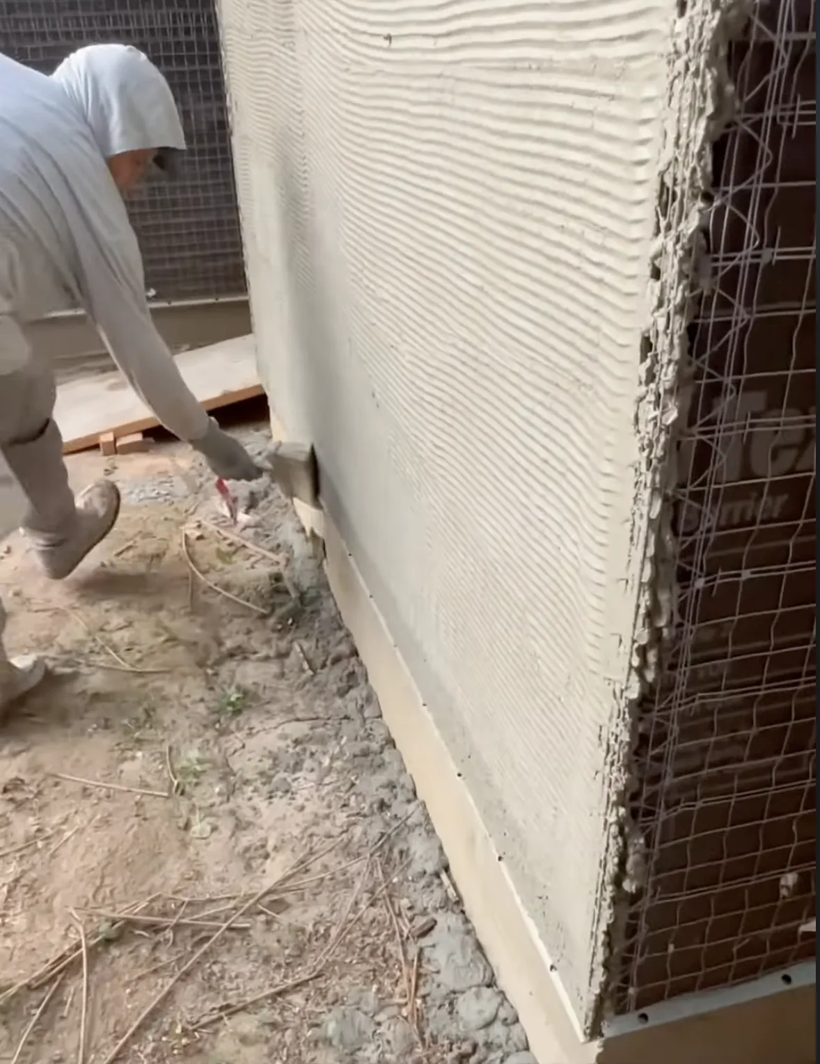 man painting grey stucco to wall