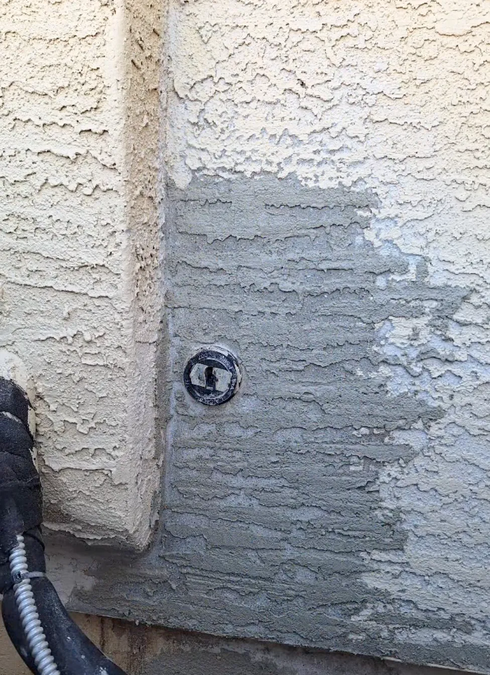 stucco repair on a tan and grey wall