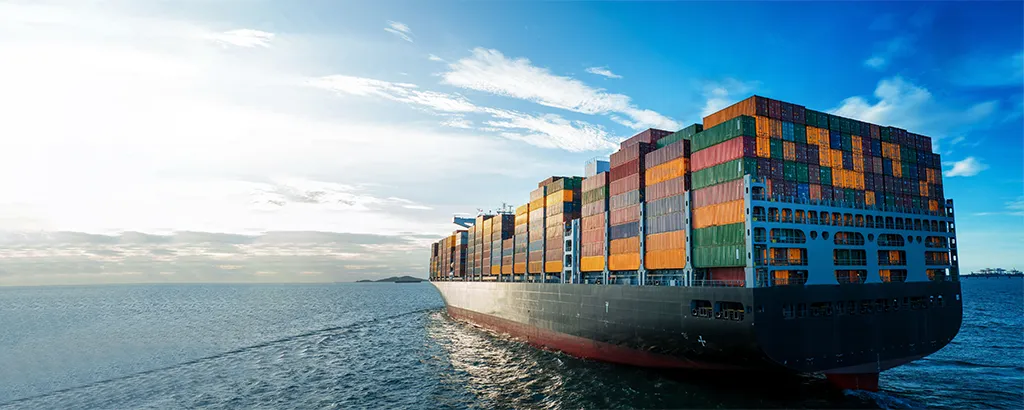 Large ocean container ship loaded with stacked shipping containers arriving at port — transpacific container shipping and port logistics for U.S. importers