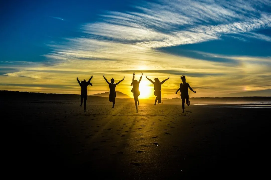 sunset with people running on a beach jumping with excitement. Creating a shadow image of the people