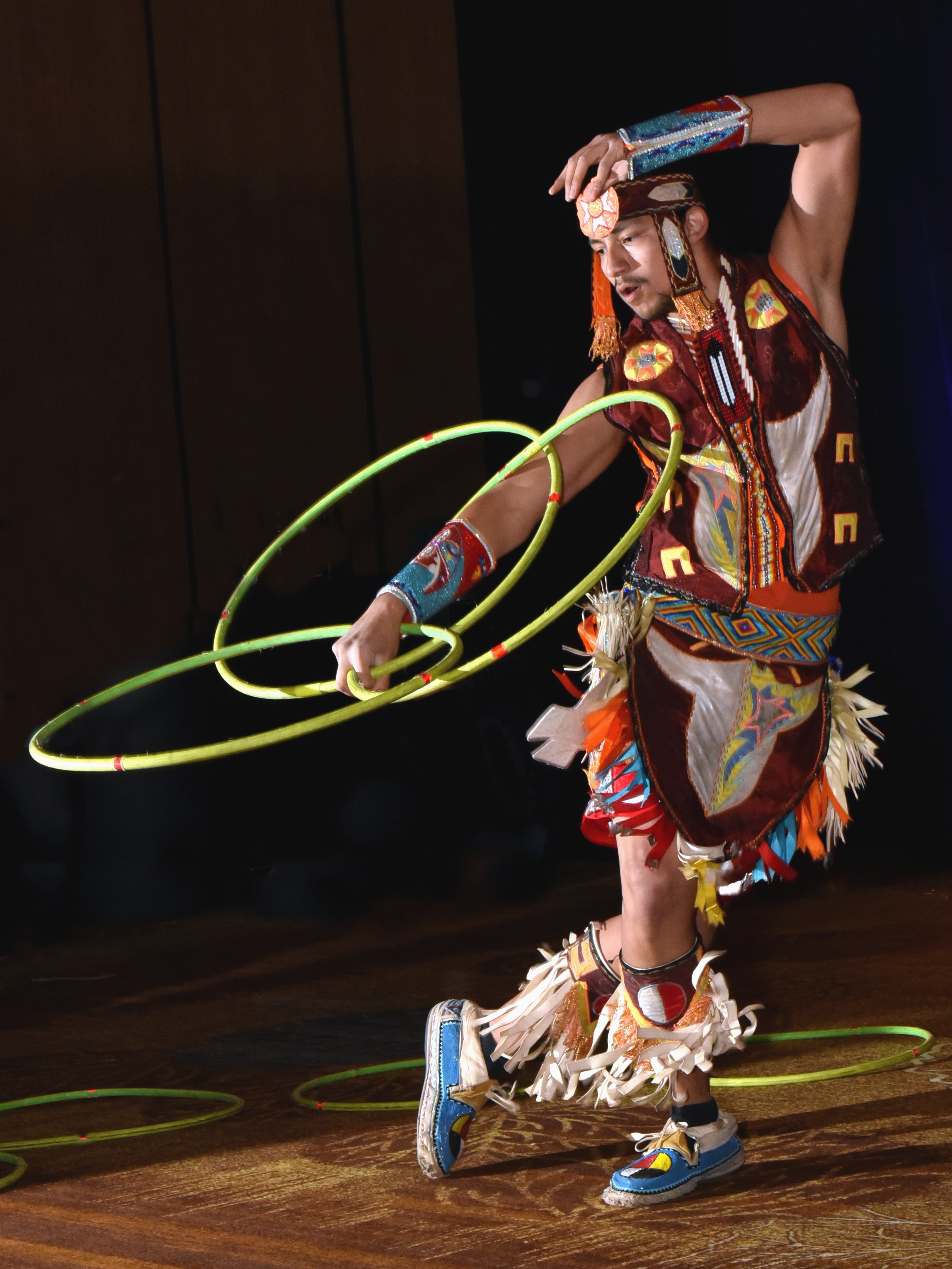 Cinematic wide shot of an Indigenous hoop dancer in dramatic lighting