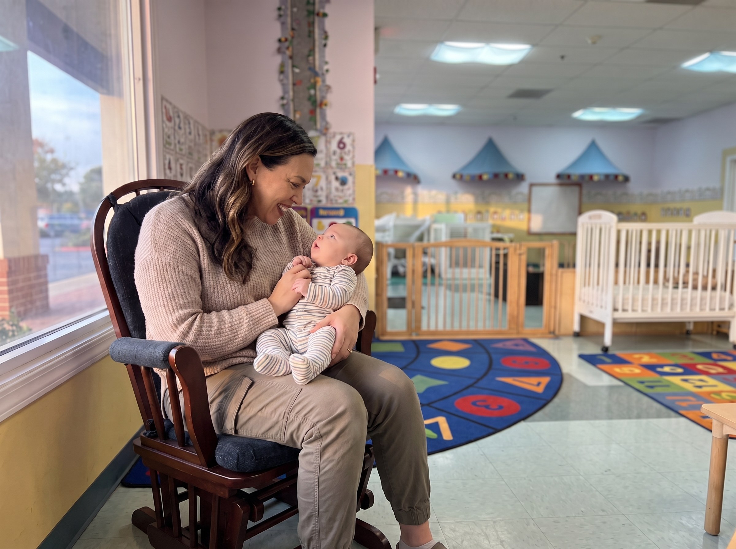 Teacher holding a baby in the infant room at Sunny Cove Preschool in Oceanside