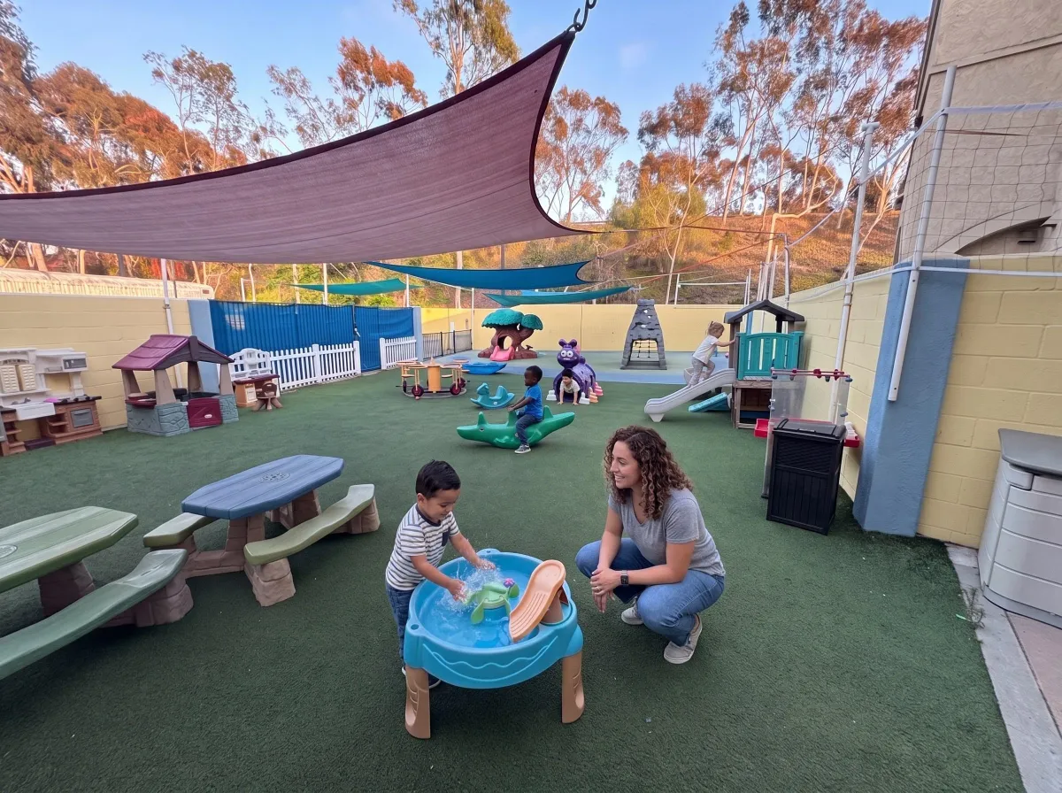 Children playing on the shaded turf playground at Sunny Cove Preschool Oceanside