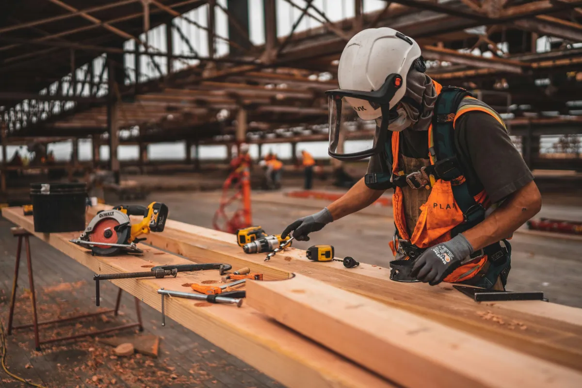 Carpenter in a hard hat cutting lumber on a job site