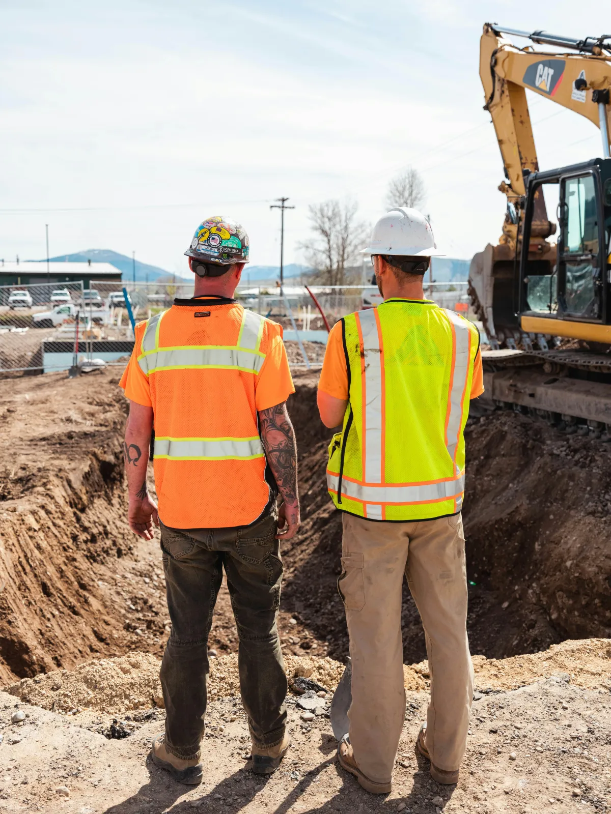 Two contractors in high-visibility vests and hard hats reviewing work at a Colorado jobsite