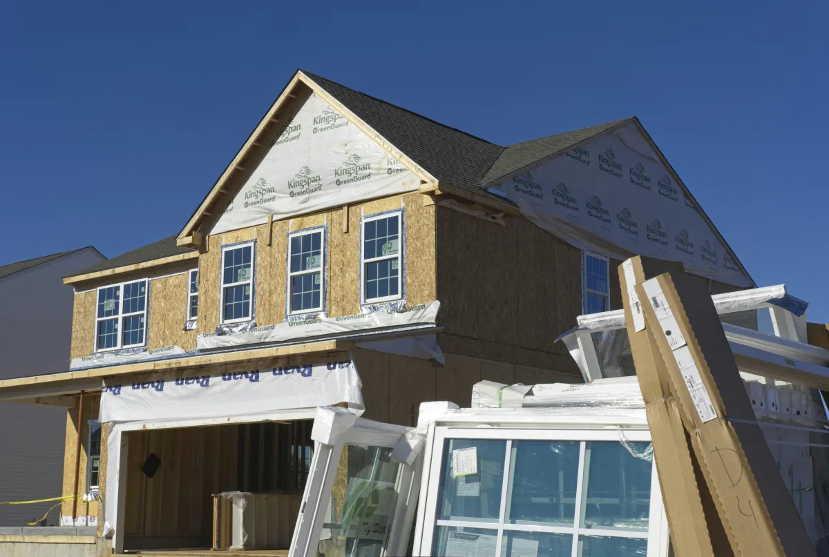 Wood-framed house under construction with windows being installed
