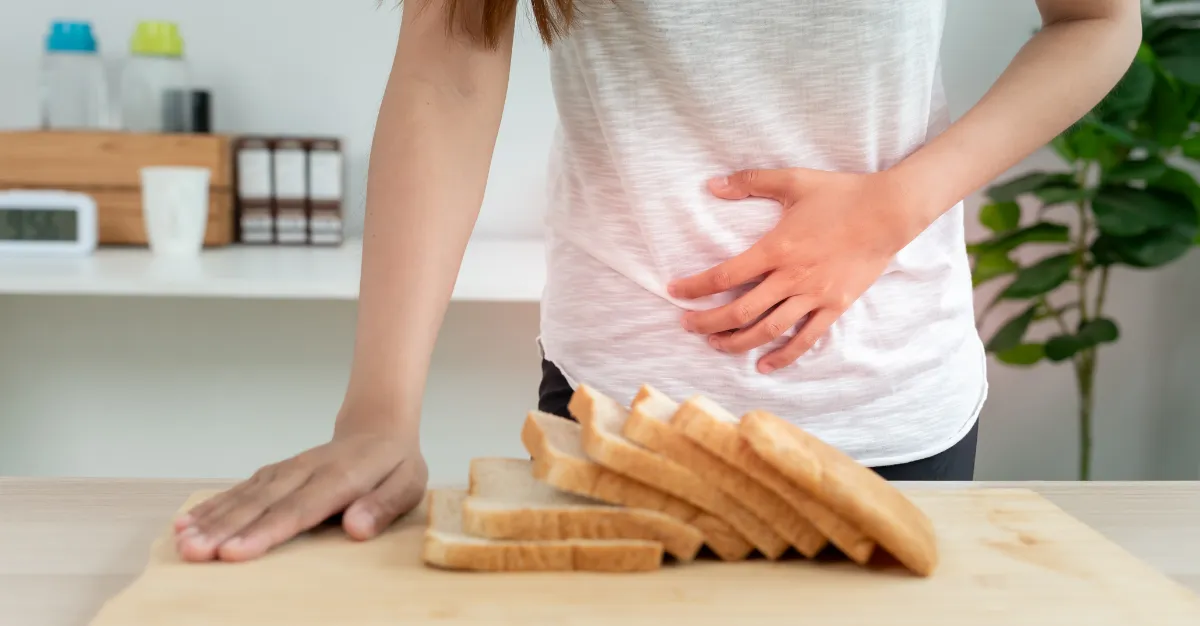person behind a loaf of bread holding stomach