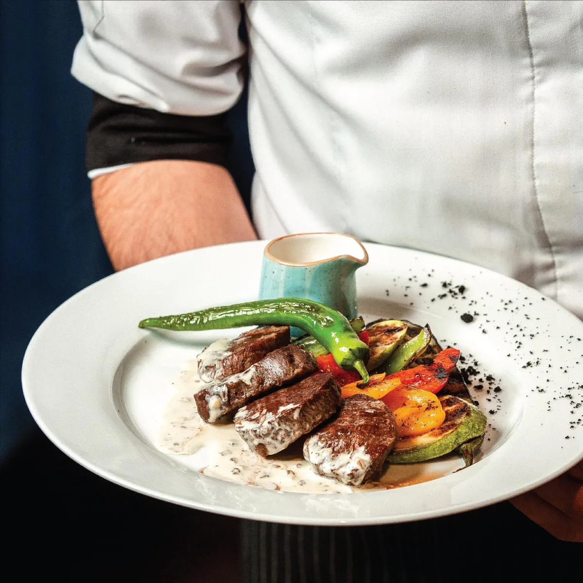 A waiter serves a dish to a guest, showcasing the warm hospitality and attentive service at R Italian Kitchen & Smokehouse.
