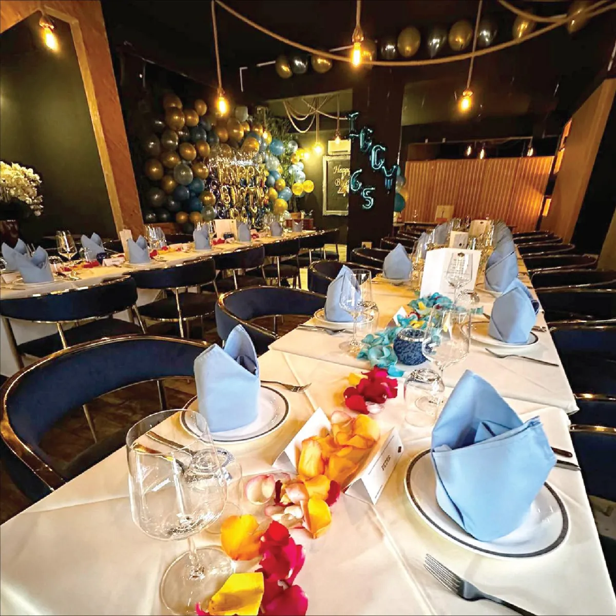 Interior of R Italian Kitchen & Smokehouse set up for a birthday celebration, featuring a long table with decorated napkins.