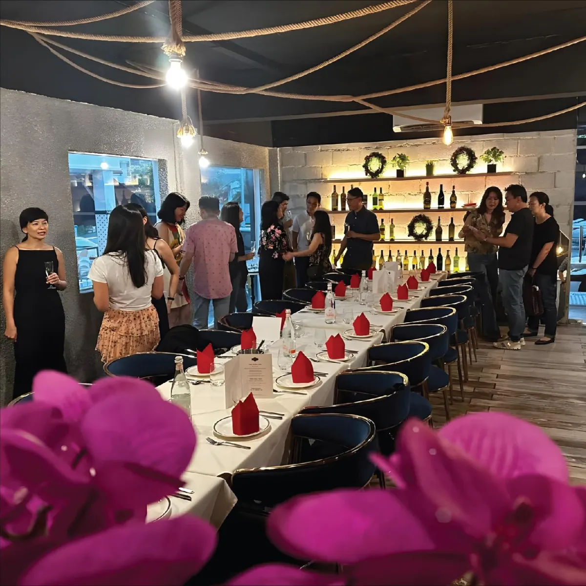 Guests enjoying a private event at the long dining table inside R Italian Kitchen & Smokehouse.
