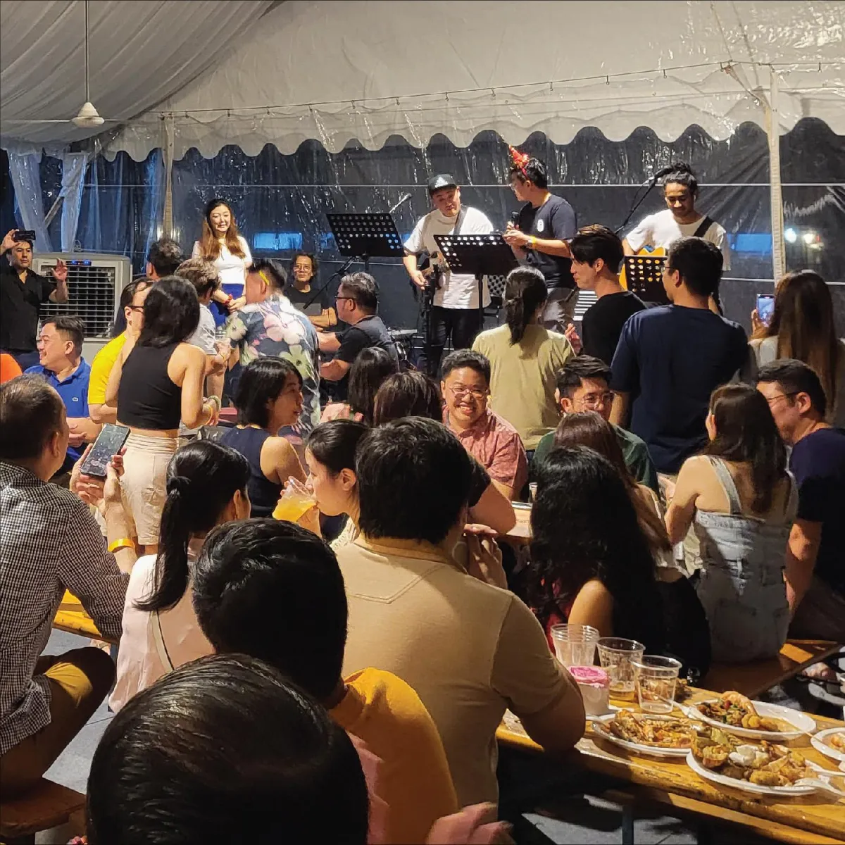 Large outdoor catering event under a tent with music, hosted by R Italian Kitchen & Smokehouse.