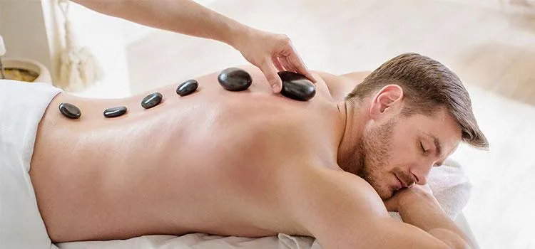 Client receiving hot stone massage with dim lighting and calming music