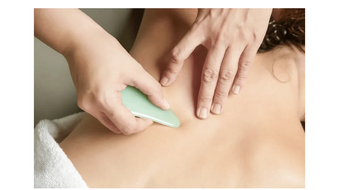 Gua sha massage tool gliding along the shoulder for pain relief