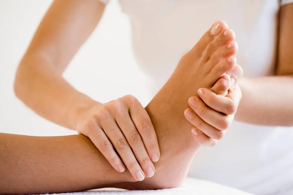 Therapist applying pressure to foot reflex zones