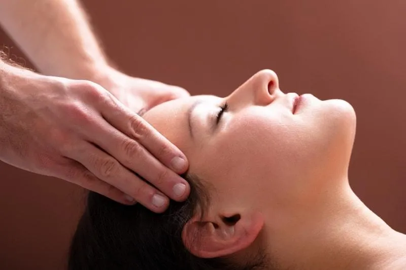 Massage therapist working on neck tension to ease headache