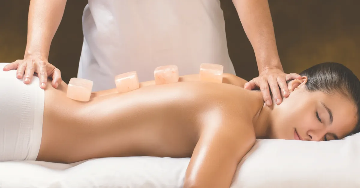 Warm pink salt stones placed along the spine during massage